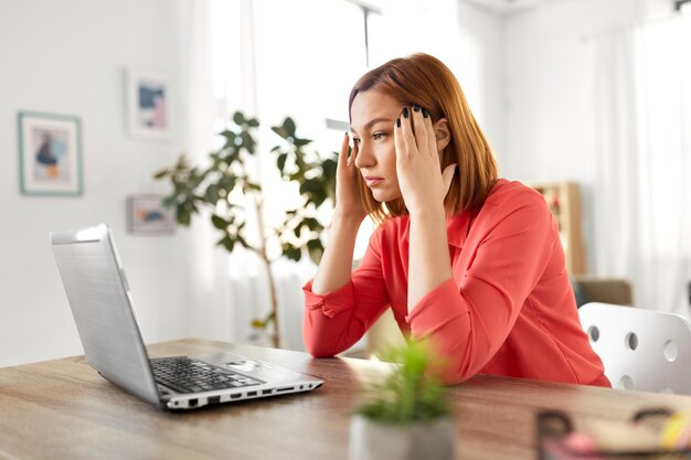 mujer estresada con computadora portátil trabajando en la oficina de casa