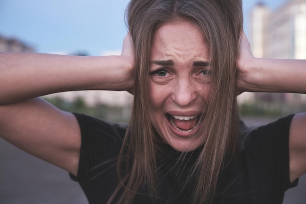 Mujer estresada y cubierta las orejas con las manos y gritando cuidado de la salud psíquica personas emociones