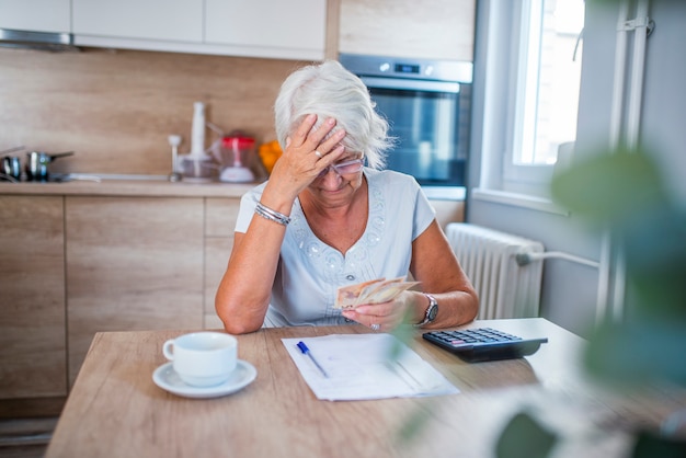 Mujer estresada senior está haciendo trabajo bancario y administrativo en casa
