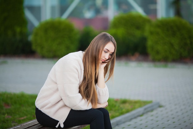 Mujer estresada por el trabajo mientras está sentada al aire libre, presione de sus colegas.