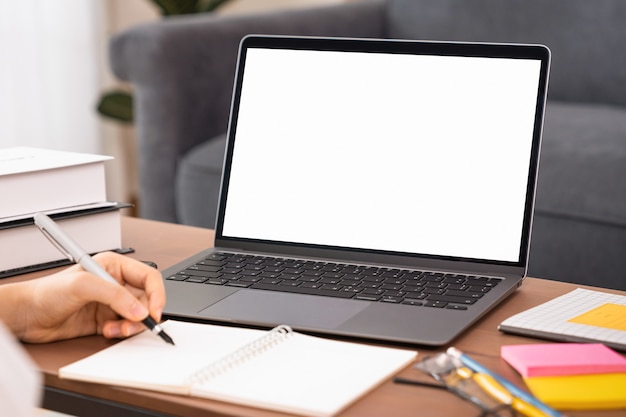 Mujer estudiando e-learning en la computadora portátil con una pantalla blanca de maqueta en la mesa de madera.