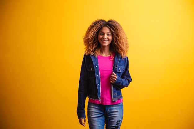 Mujer estudiante africana sonriendo sobre fondo amarillo.