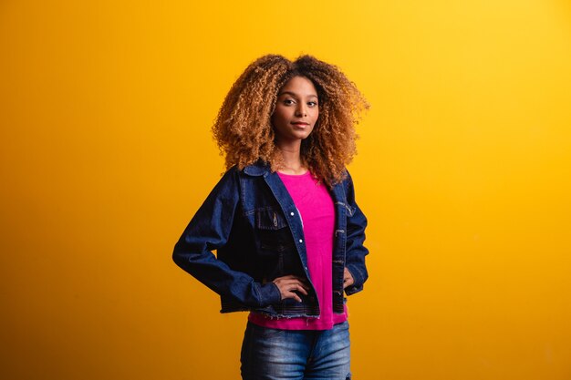 Mujer estudiante africana sonriendo sobre fondo amarillo.