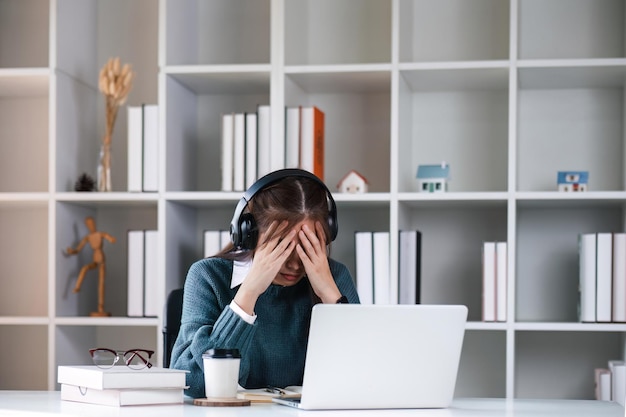 Mujer estudiante cansada con una computadora portátil quejándose sentada en un escritorio en la sala de estar de casa