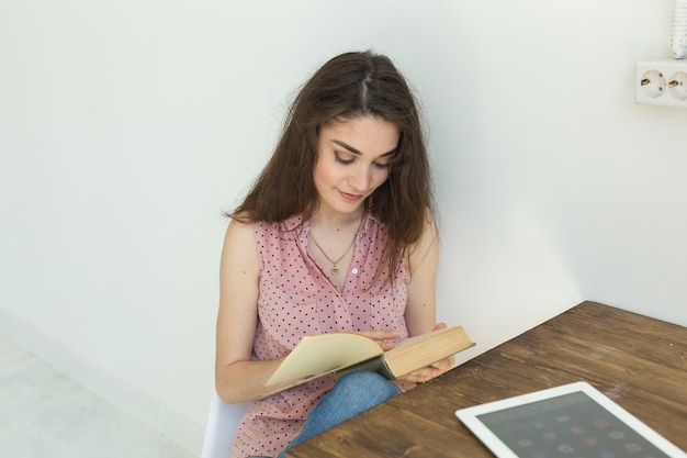 Mujer estudiante está leyendo un libro en una habitación blanca