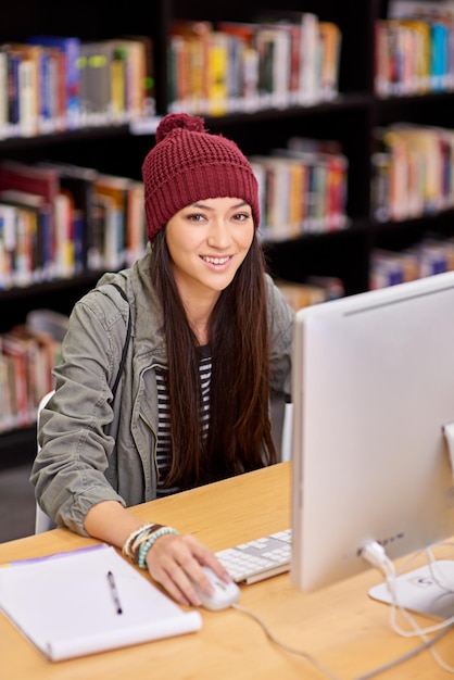 Mujer y estudiante felices con computadora en la biblioteca de la universidad para el estudio de cursos en línea e investigación para la educación superior Aprendizaje a distancia de personas femeninas y clase virtual para acceso tecnológico con beca