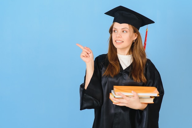 Mujer estudiante graduada vistiendo toga y sombrero de graduación, sobre fondo azul.