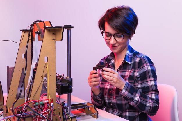 Una mujer estudiante imprime un prototipo en una impresora.