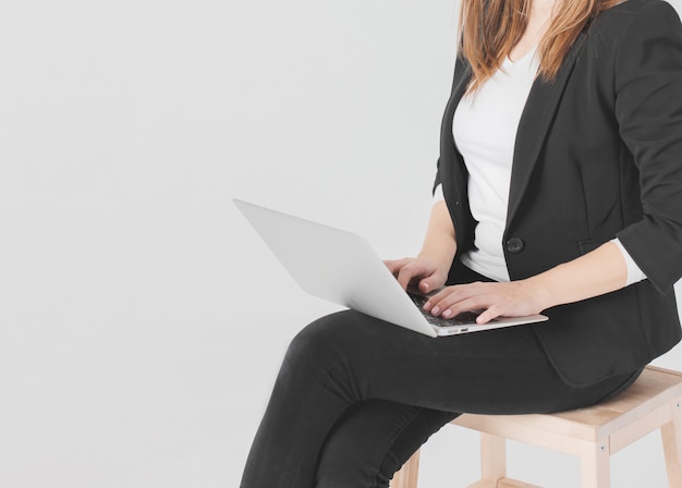 Mujer estudiante de negocios en traje negro trabajando en laptop