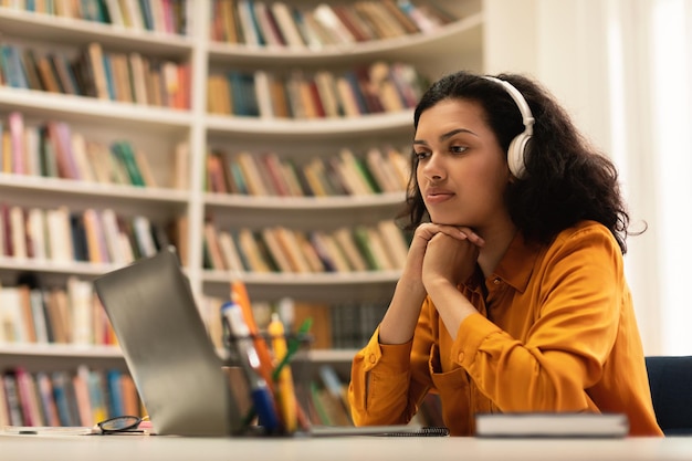 Mujer estudiante pensativa mirando la computadora portátil aprendiendo en línea teniendo una clase remota con distante