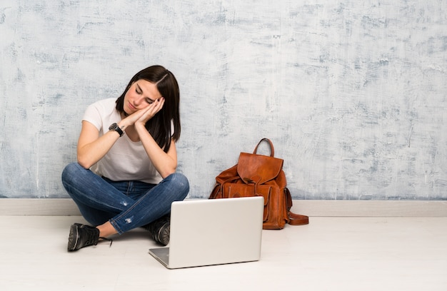 Mujer estudiante sentada en el suelo haciendo gesto de sueño en expresión dorable