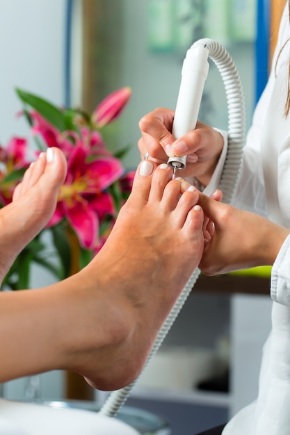 Mujer en estudio de uñas recibiendo pedicura