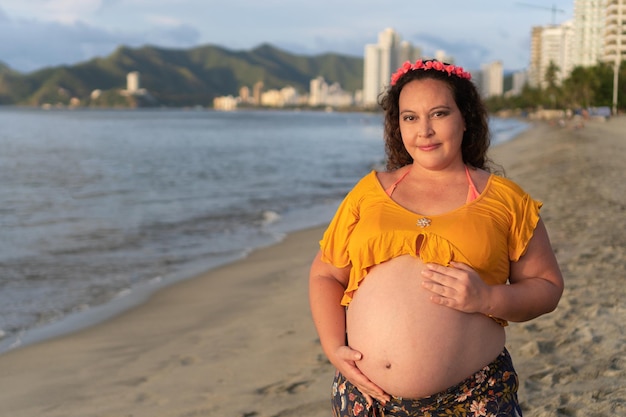 Mujer étnica embarazada feliz en la playa