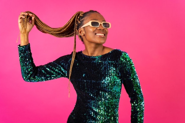 Mujer étnica negra con fiesta de trenzas bailando sobre fondo rosa divirtiéndose en gafas