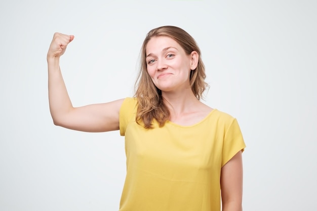Mujer europea alegre positiva que muestra los músculos de la mano Mujer caucásica de mediana edad con ropa informal flexionando bíceps