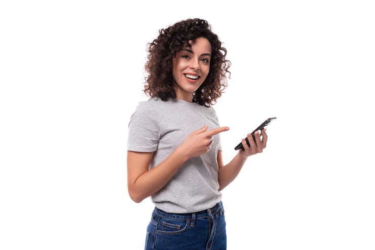 Foto mujer europea bien cuidada con cabello rizado negro en una camiseta básica gris hablando en las redes sociales