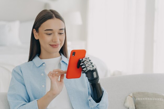 Mujer europea feliz con brazo artificial biónico charlando en el desarrollo de innovación de teléfonos inteligentes