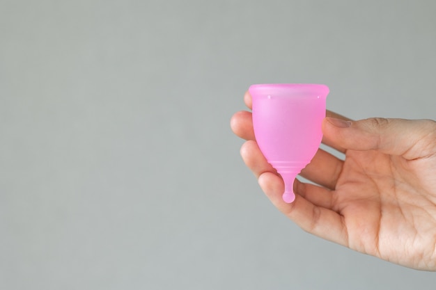 Una mujer europea sostiene una copa menstrual rosa hecha de silicona en sus manos