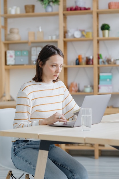 Una mujer europea en su oficina en casa está trabajando con una computadora portátil o viendo un seminario web