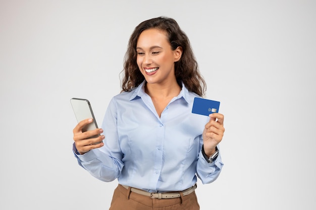 Foto mujer europea en el trabajo usando teléfono y tarjeta de crédito