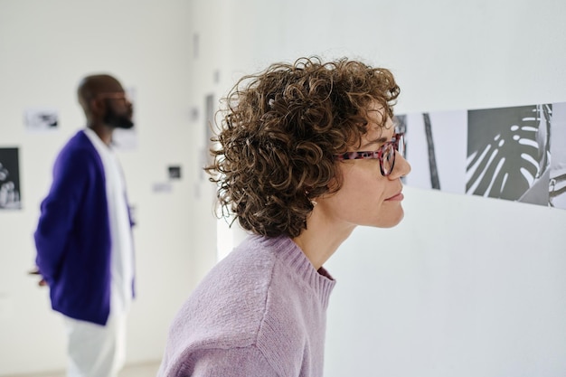 Mujer examinando cuadros modernos en la galería