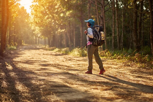 Foto mujer excursionista caminando por el campo contra los árboles