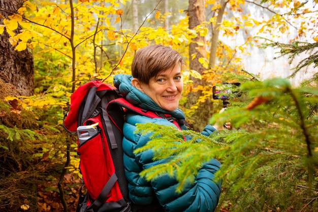 Mujer excursionista se está tomando una selfie en el bosque de otoño