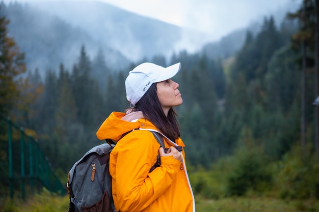 Mujer en excursionista impermeable amarillo en las montañas de otoño