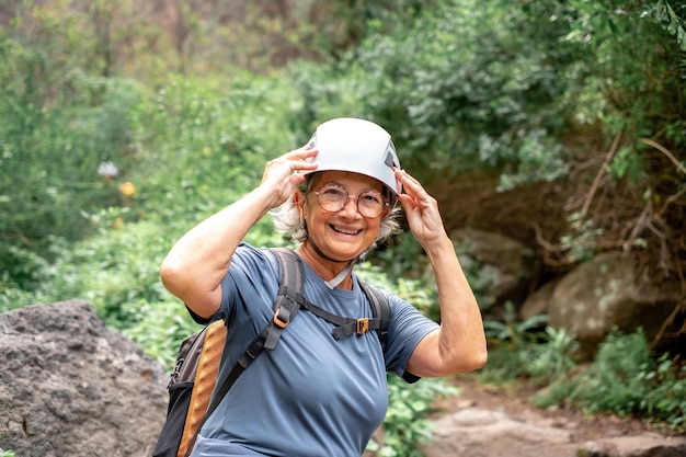 Mujer excursionista senior sonriente con casco en un turista de día de trekking en vacaciones disfrutando de la libertad
