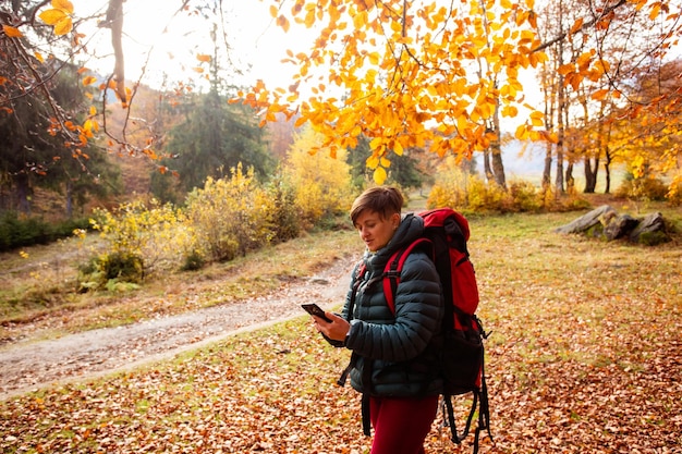 La mujer excursionista usa la navegación en el teléfono inteligente mientras viaja