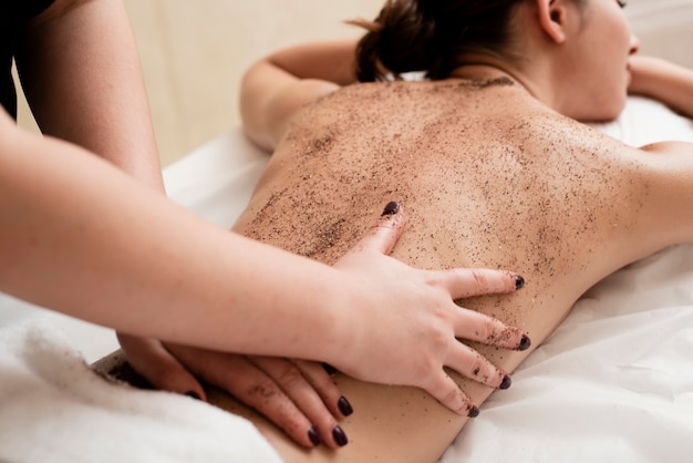 Mujer exfoliando su espalda en el spa