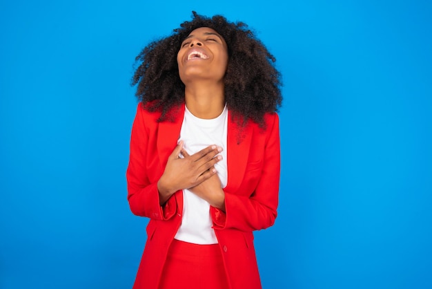 Mujer expresa felicidad se ríe agradablemente mantiene las manos en el corazón