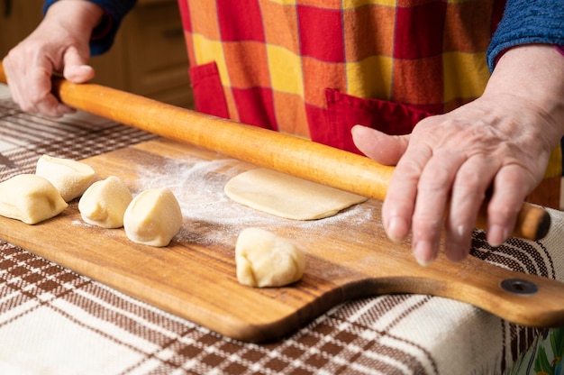 Mujer extendiendo la masa con un rodillo sobre la mesa de la cocina.