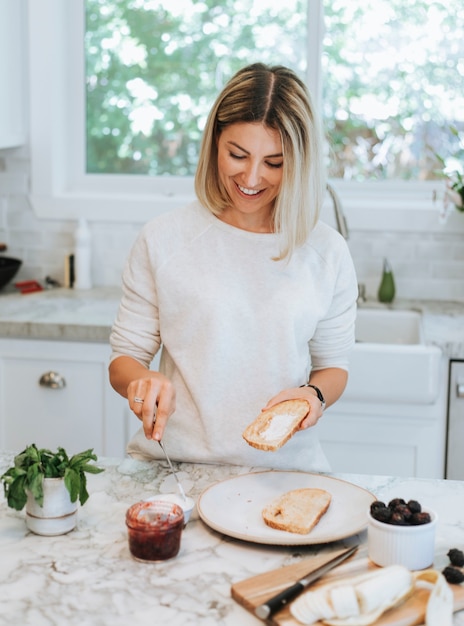 Mujer extendiendo queso crema vegano sobre una tostada