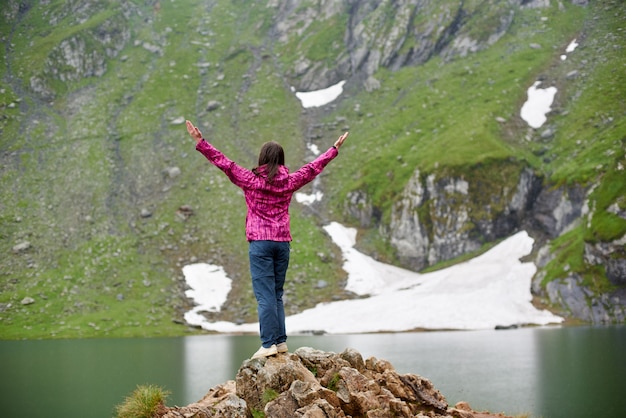 Mujer extendiendo sus brazos con entusiasmo disfrutando de impresionantes vistas sobre el lago Vidraru