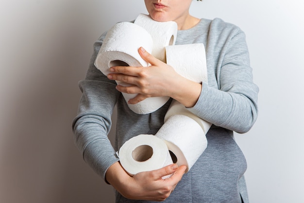 La mujer extiende hacia adelante muchos rollos de papel higiénico.