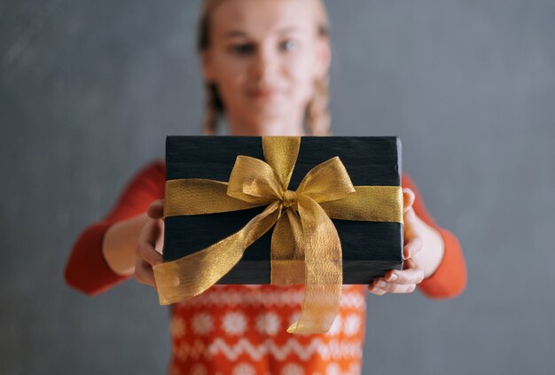 Mujer extiende su mano con una caja de regalo y da un regalo