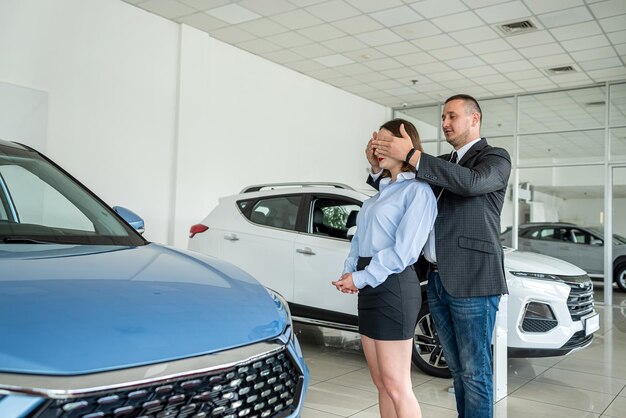 una mujer extremadamente feliz está feliz cuando su marido compró un coche en un concesionario de automóviles