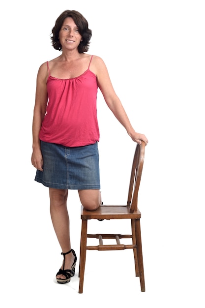 Mujer en falda de mezclilla jugando con una silla sobre fondo blanco.