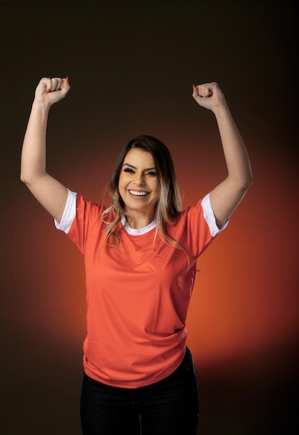 Mujer fanática del fútbol animando a su club favorito y al equipo de la copa mundial de fondo naranja