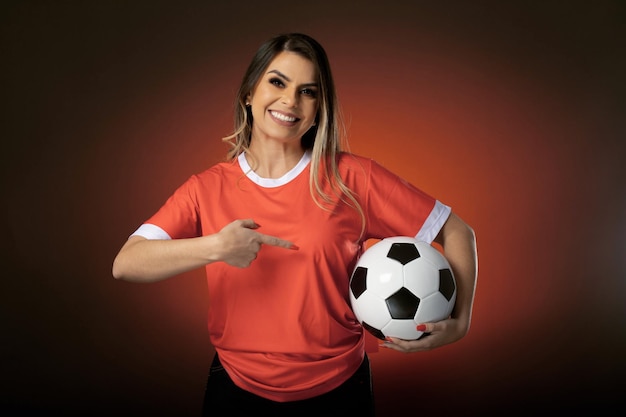 Mujer fanática del fútbol animando a su club favorito y al equipo de la copa mundial de fondo naranja