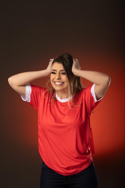 Mujer fanática del fútbol animando a su club favorito y al equipo de la copa mundial de fondo rojo