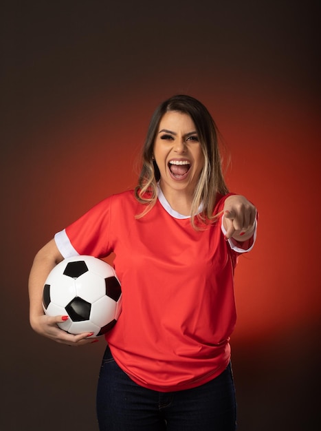 Mujer fanática del fútbol animando a su club favorito y al equipo de la copa mundial de fondo rojo