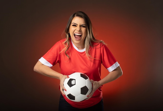 Mujer fanática del fútbol animando a su club favorito y al equipo de la copa mundial de fondo rojo