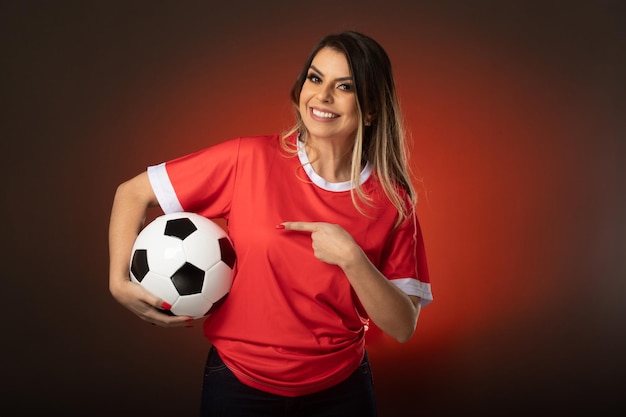 Mujer fanática del fútbol animando a su club favorito y al equipo de la copa mundial de fondo rojo