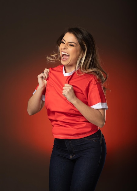 Mujer fanática del fútbol animando a su club favorito y al equipo de la copa mundial de fondo rojo