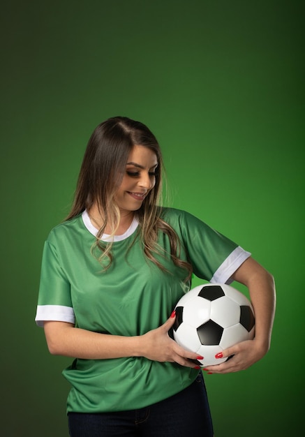 Mujer fanática del fútbol animando a su club favorito y al equipo mundial de fondo verde