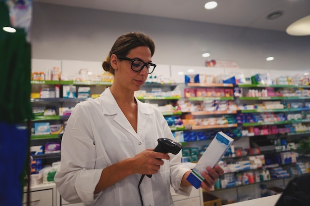 Mujer farmacéutica con anteojos trabaja en el mostrador de la farmacia