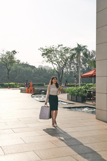 Mujer fashionmonger feliz con bolsas de compras caminando por la calle