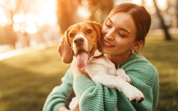 Mujer feliz abrazando al perro beagle en el parque